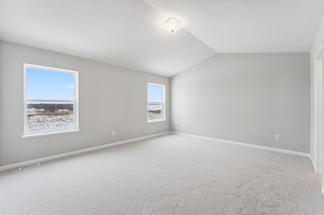 spare room featuring baseboards, visible vents, lofted ceiling, a textured ceiling, and carpet flooring