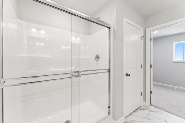 full bath with marble finish floor, a shower stall, and baseboards