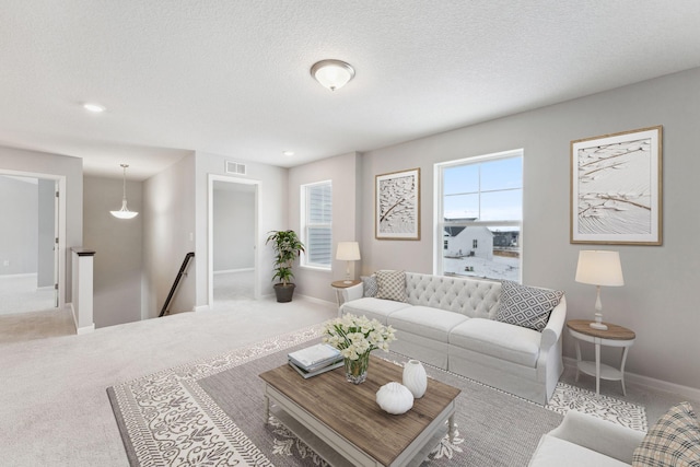 carpeted living area with a textured ceiling, visible vents, and baseboards