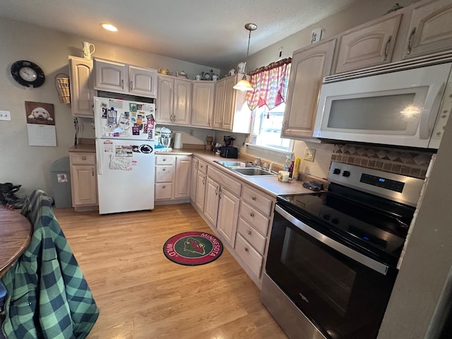 kitchen with decorative light fixtures, sink, white appliances, and light hardwood / wood-style flooring