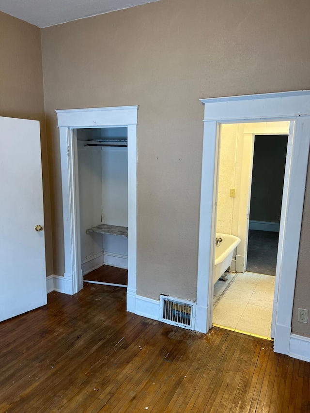 unfurnished bedroom featuring hardwood / wood-style flooring, a closet, and ensuite bathroom