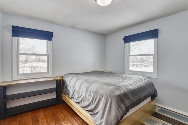 bedroom with multiple windows, baseboards, and dark wood-style flooring