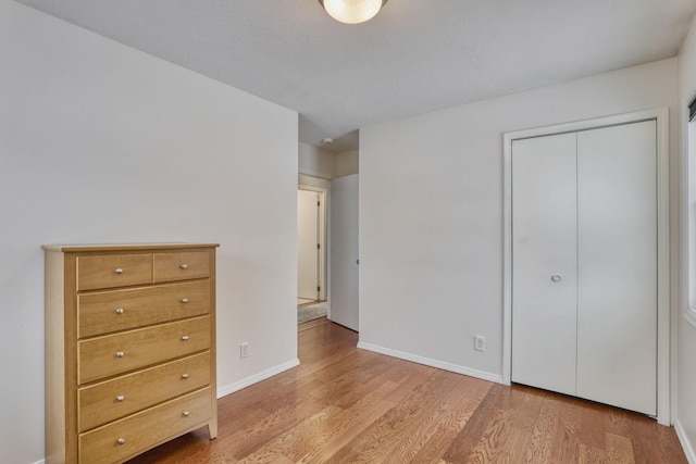 unfurnished bedroom featuring a closet, baseboards, and wood finished floors