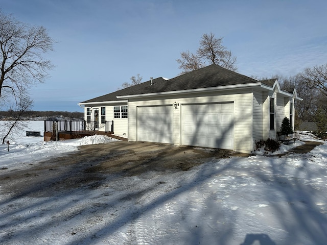 view of snowy exterior with a garage and a deck