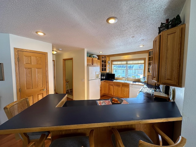 kitchen featuring white appliances, kitchen peninsula, sink, and a textured ceiling