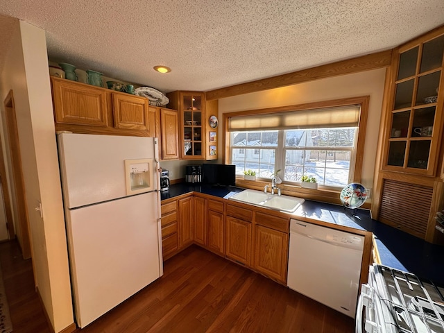 kitchen featuring white appliances, dark hardwood / wood-style floors, sink, and a textured ceiling