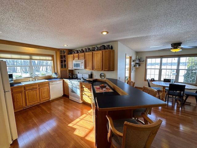 kitchen featuring sink, a textured ceiling, dark hardwood / wood-style floors, kitchen peninsula, and white appliances