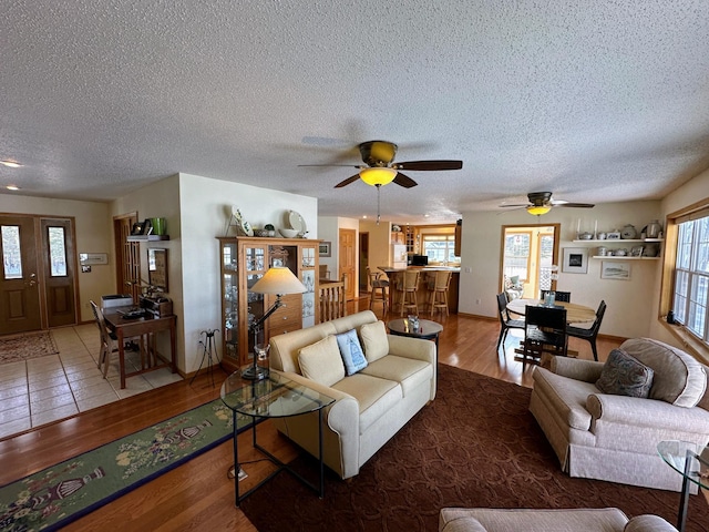 living room with hardwood / wood-style flooring, ceiling fan, and a textured ceiling