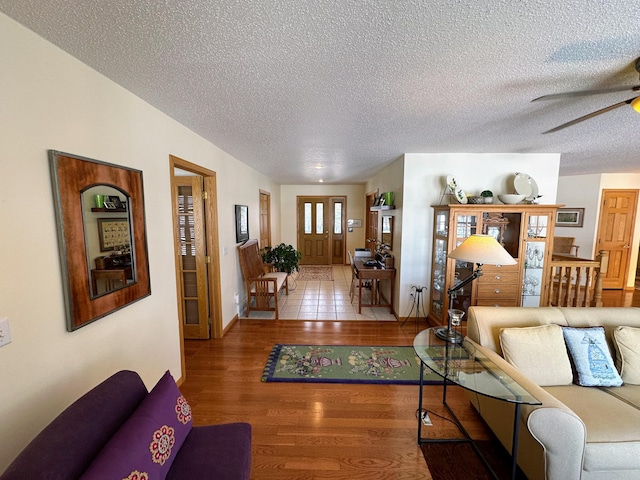 living room with hardwood / wood-style flooring, a textured ceiling, and ceiling fan