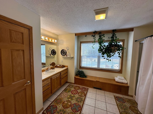 bathroom with a healthy amount of sunlight, vanity, tile patterned flooring, and a textured ceiling