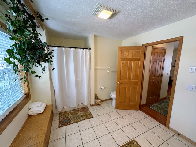 bathroom with tile patterned flooring, a textured ceiling, toilet, and a shower with shower curtain