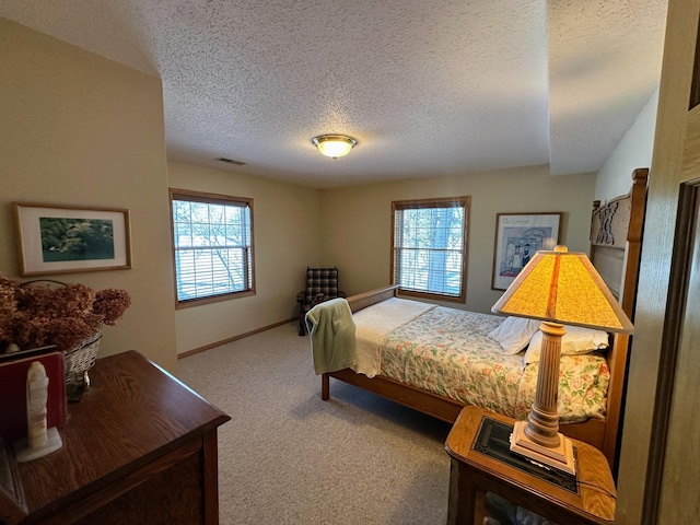 bedroom featuring light colored carpet, multiple windows, and a textured ceiling