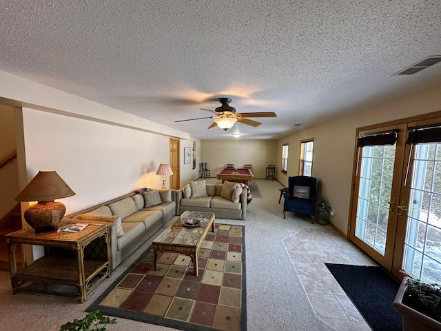 living room featuring ceiling fan, a textured ceiling, and french doors