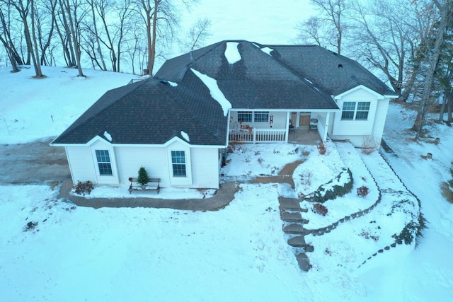 snow covered back of property with a porch