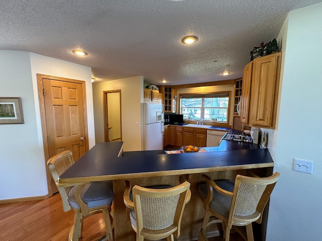 43561 Paul Lake Dr, Edna Twp, MN 56573 - kitchen with white appliances, a sink, a peninsula, a textured ceiling, and light wood-style floors