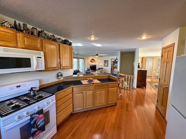 43561 Paul Lake Dr, Edna Twp, MN 56573 - kitchen with white appliances, a peninsula, light wood-style flooring, recessed lighting, and ceiling fan