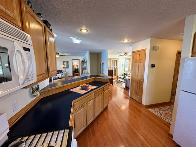43561 Paul Lake Dr, Edna Twp, MN 56573 - kitchen featuring ceiling fan, white appliances, a peninsula, light wood finished floors, and a textured ceiling