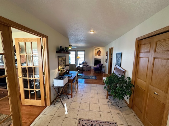 43561 Paul Lake Dr, Edna Twp, MN 56573 - living room with a tile fireplace, light tile patterned flooring, a textured ceiling, and a ceiling fan