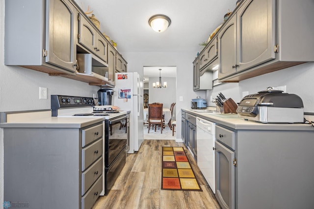 kitchen featuring gray cabinetry, an inviting chandelier, white appliances, and light hardwood / wood-style floors