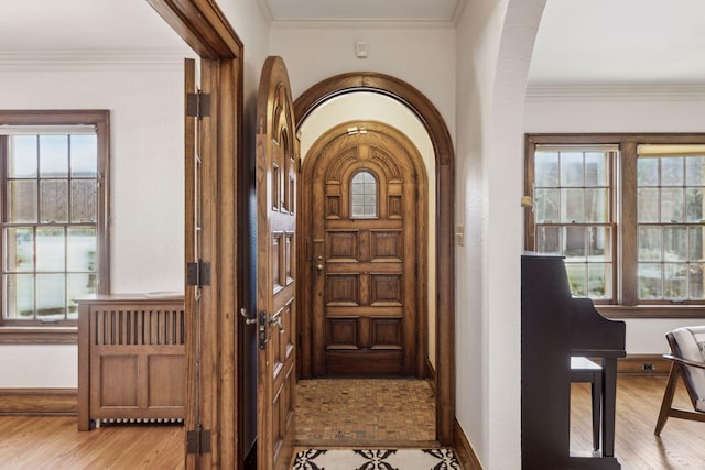 foyer entrance with crown molding and light hardwood / wood-style flooring