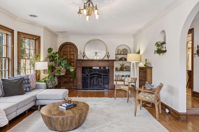 living room featuring hardwood / wood-style flooring, a premium fireplace, a chandelier, and crown molding