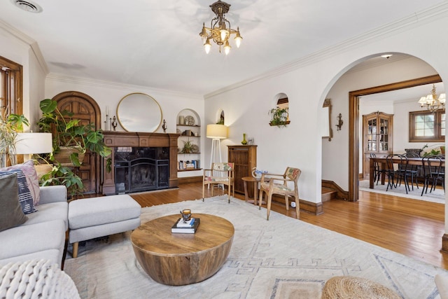 living room featuring a fireplace, wood-type flooring, ornamental molding, and a chandelier