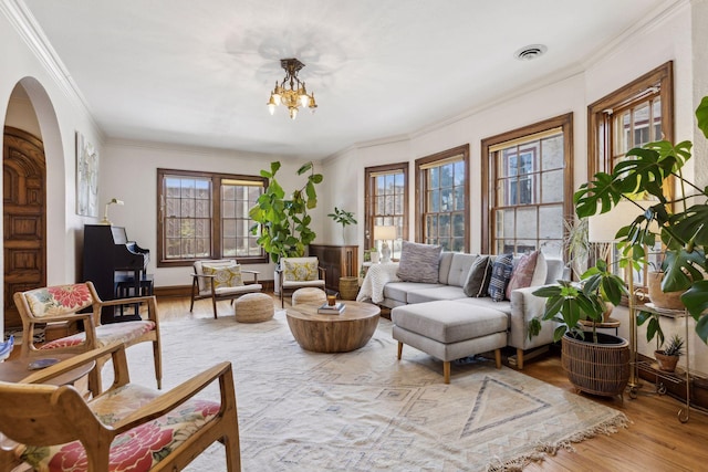 living room with ornamental molding, a chandelier, and light hardwood / wood-style flooring