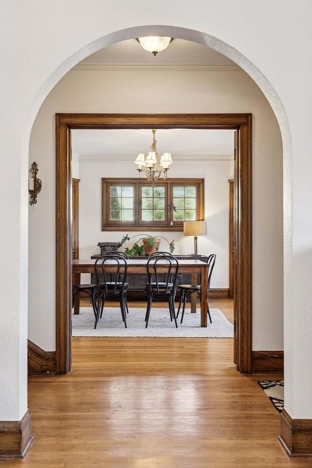 dining room with a notable chandelier, crown molding, and light hardwood / wood-style flooring