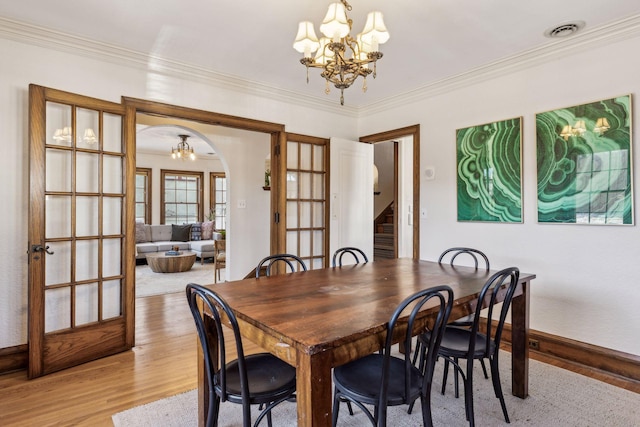 dining space featuring ornamental molding, wood-type flooring, and a notable chandelier