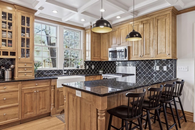 kitchen with sink, a breakfast bar, stove, dark stone countertops, and decorative light fixtures