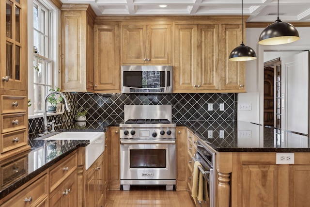 kitchen featuring sink, decorative light fixtures, dark stone counters, and appliances with stainless steel finishes