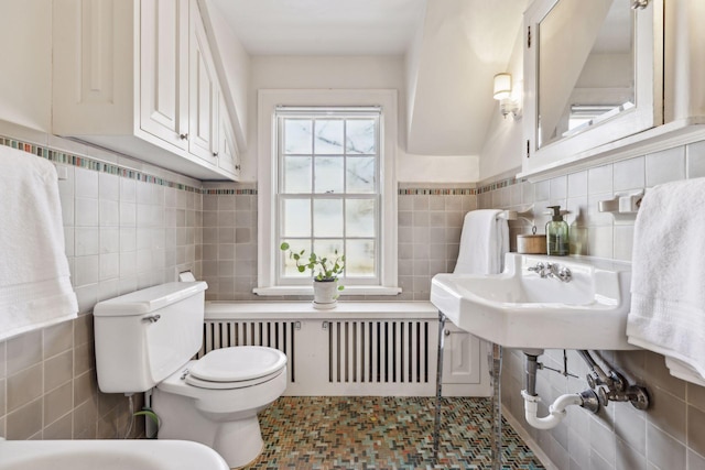 bathroom featuring radiator heating unit, toilet, and tile walls