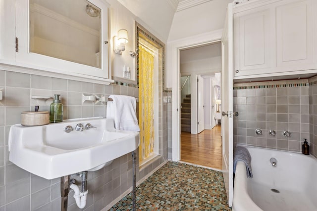 bathroom featuring ornamental molding, tile walls, and a tub to relax in