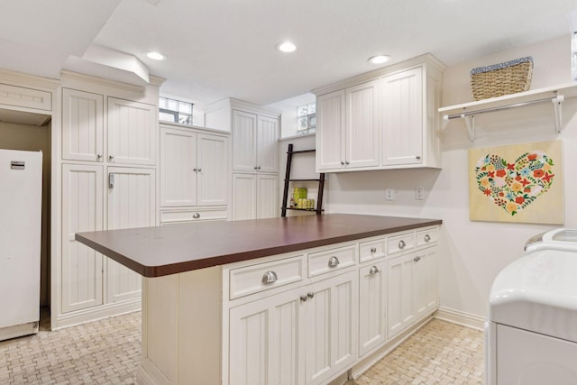 kitchen with white refrigerator, washer / dryer, and white cabinets