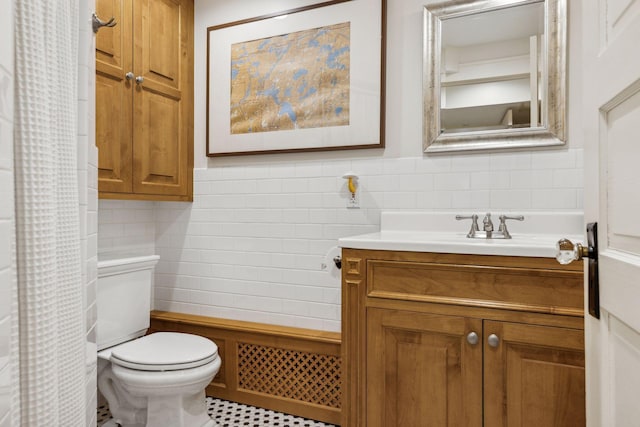 bathroom featuring vanity, tile walls, and toilet