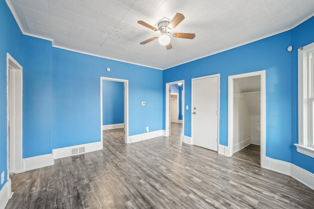 empty room featuring crown molding, wood-type flooring, and ceiling fan