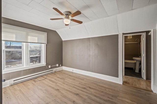 bonus room featuring lofted ceiling, light wood-type flooring, a baseboard radiator, wooden walls, and ceiling fan