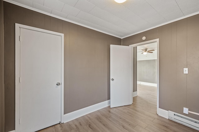 unfurnished bedroom featuring crown molding, a baseboard heating unit, and light hardwood / wood-style floors