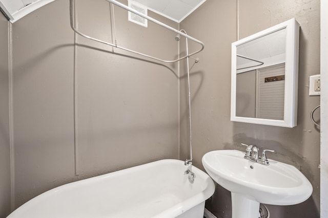 bathroom with crown molding, a bath, and sink