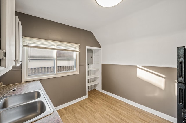 kitchen featuring lofted ceiling, sink, and light hardwood / wood-style flooring