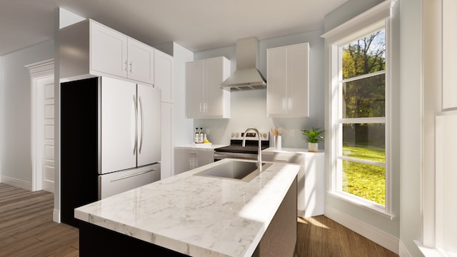 kitchen featuring wall chimney range hood, white cabinetry, fridge, and sink