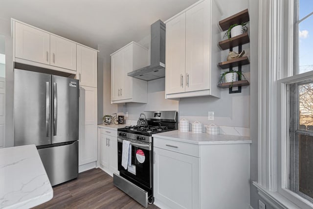 kitchen with dark wood-type flooring, white cabinetry, stainless steel appliances, light stone countertops, and wall chimney exhaust hood