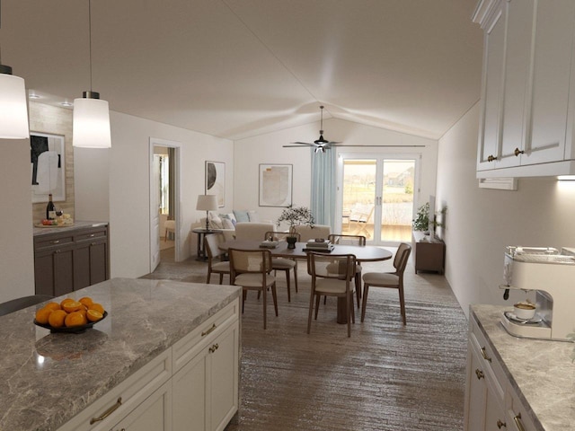 interior space with white cabinets, decorative light fixtures, light stone counters, and lofted ceiling