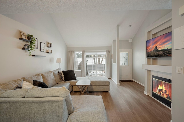 living room featuring hardwood / wood-style flooring, a tile fireplace, lofted ceiling, and a textured ceiling