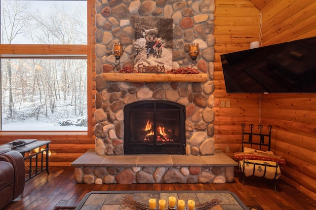 living room featuring a stone fireplace, log walls, plenty of natural light, and dark hardwood / wood-style flooring