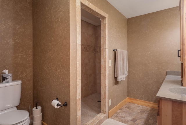 bathroom featuring tiled shower, toilet, and vanity