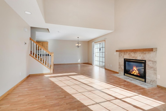 unfurnished living room with a chandelier, a fireplace, and light hardwood / wood-style flooring