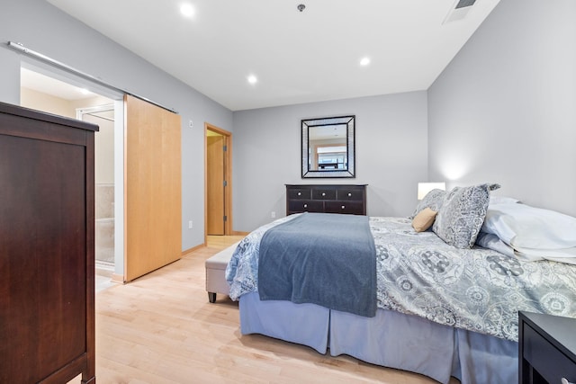 bedroom featuring ensuite bathroom and light hardwood / wood-style flooring