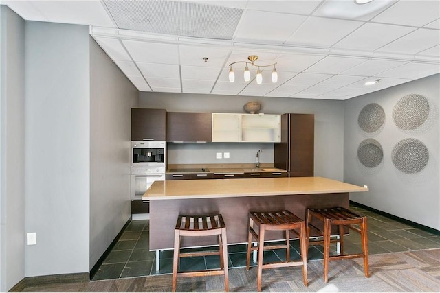 kitchen featuring stainless steel double oven, fridge, sink, a kitchen breakfast bar, and a center island