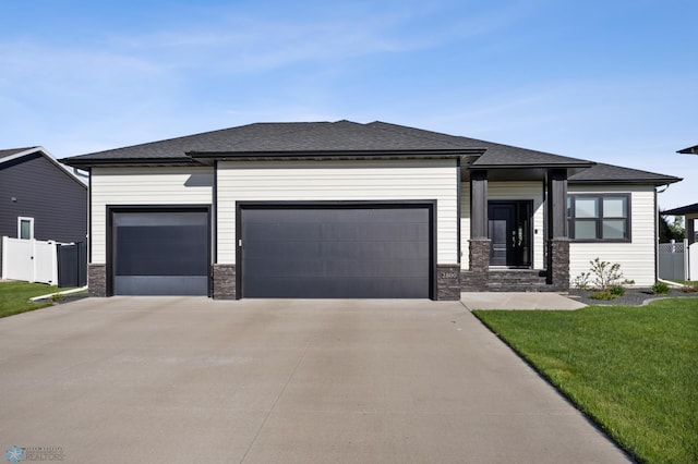 prairie-style house with an attached garage, driveway, and a shingled roof